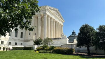 View of the U.S. Supreme Court building with the dome of the Library of Congress building in the distance